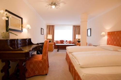 a hotel room with two beds and a piano at A-ROSA Hotel Thurnher's Alpenhof in Zürs am Arlberg