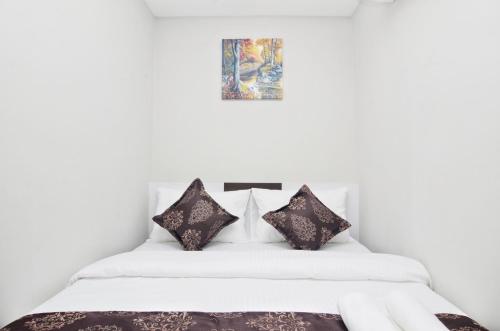 a bedroom with a white bed with black pillows at K VILA HOTEL in Sungai Petani