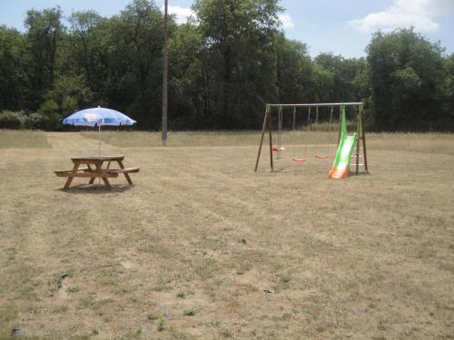 a picnic table with an umbrella next to a playground at Gite Au Chant des Vents in Thurageau