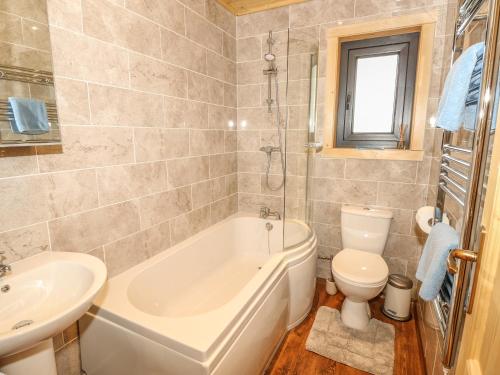 a bathroom with a tub and a toilet and a sink at Chale Farm Lodge in Ventnor
