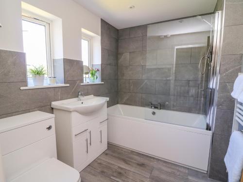Un baño con bañera blanca y lavabo. en Owl Cottage, en Llandrindod Wells
