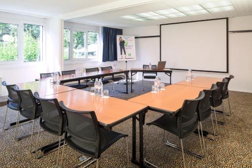 a conference room with tables and chairs and a white screen at ibis Styles Besançon in Besançon