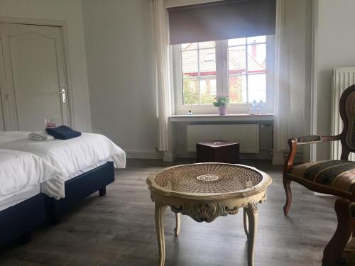 a bedroom with a bed and a table and a window at Maison Blanche in Wielsbeke