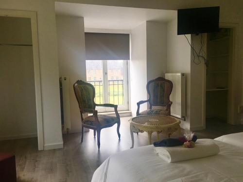 a bedroom with two chairs and a bed and a window at Maison Blanche in Wielsbeke