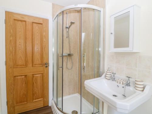 a bathroom with a shower and a sink and a mirror at Glyn Ewryd in Bodewryd