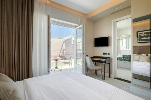 a hotel room with a bed and a desk and a balcony at Athenian Foss in Athens