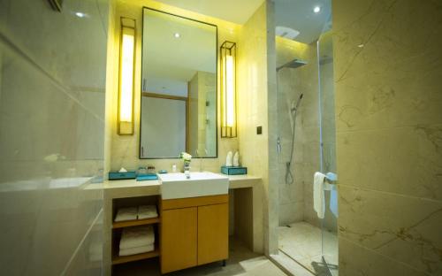 a bathroom with a sink and a shower and a mirror at Days Hotel by Wyndham Shanxi Xinzhou in Xinzhou