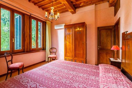 a bedroom with a large pink bed with two chairs at Agriturismo Settepassi Tuscany in Ponte Buggianese