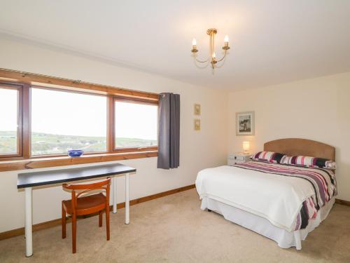 um quarto com uma cama, uma secretária e uma janela em Taigh Cruinneachadh Gathering Place em Dunbeath