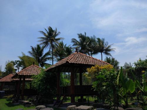 a playground with two gazebos and palm trees at JOGLO Greenhouse in Ngemplak