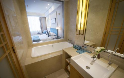 a bathroom with a tub and a sink and a mirror at Days Hotel by Wyndham Shanxi Xinzhou in Xinzhou