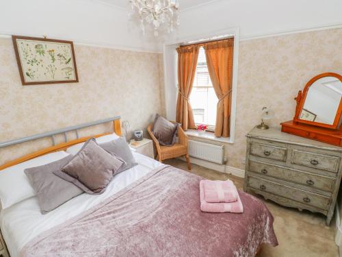 um quarto com uma cama, um espelho e uma cómoda em Castle School House em Kidwelly