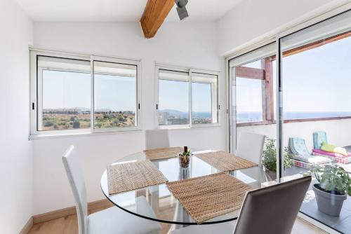 une salle à manger avec une table en verre, des chaises et des fenêtres dans l'établissement Appartement cosy Verduron vue mer panoramique, à Marseille