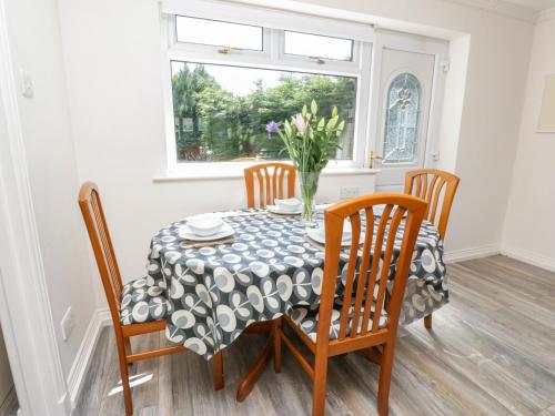 a dining room table with chairs and a vase of flowers at Mardan in Dumfries