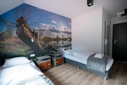 dwa łóżka w pokoju z obrazem na ścianie w obiekcie Chutor Nad Narwią w mieście Ploski
