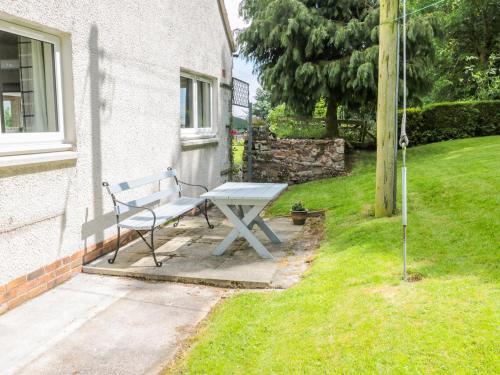 a bench sitting in the grass next to a house at Falla Farmhouse in Jedburgh