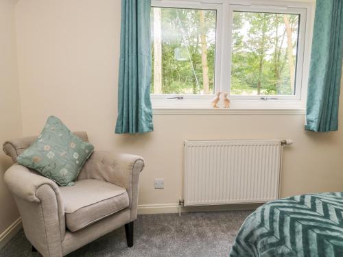 a bedroom with a chair and a window at Falla Farmhouse in Jedburgh
