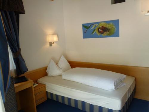 a small bed in a room with a picture on the wall at Hotel Rotwand in Laives