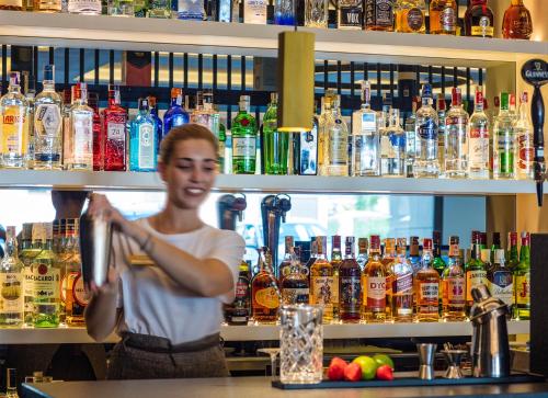 a woman standing at a bar preparing a drink at Golden Costa Salou - Adults Only 4* Sup in Salou