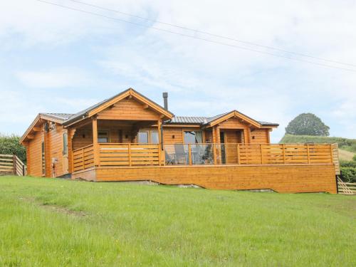 a log cabin with a large deck in a field at Manor Farm Lodges - Dragon Lodge in Newtown