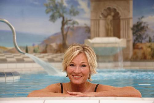 a woman sitting in a swimming pool at Thermenhotel Apollo in Bad Füssing