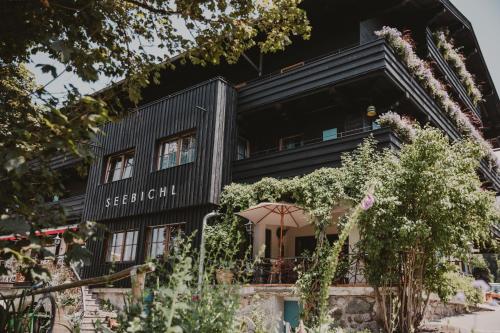 a black house with flowers in front of it at SEEBICHL haus am see Designhotel Kitzbühel in Kitzbühel