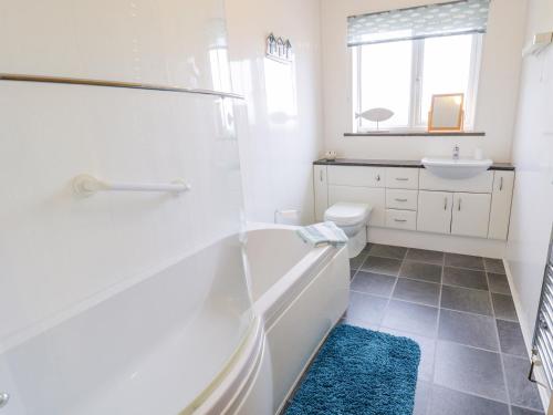 a bathroom with a tub and a toilet and a sink at Pen Bryn in Llanallgo