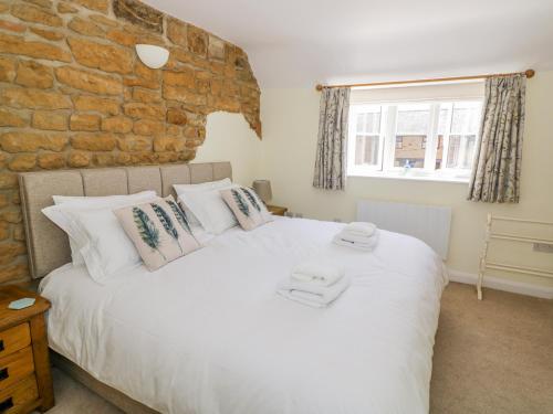 ein Schlafzimmer mit einem großen weißen Bett und einer Steinmauer in der Unterkunft Treacle Cottage in Warwick