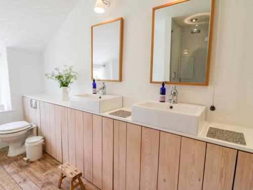 a bathroom with two sinks and a mirror at Whitehall Farm Cottage in Honiton