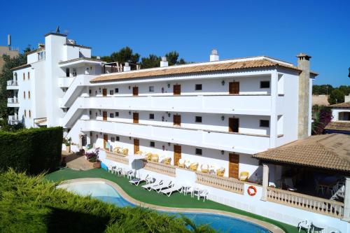 a large white building with a swimming pool and chairs at Apartaments Sa Torre by SUREDA MAS in Canyamel