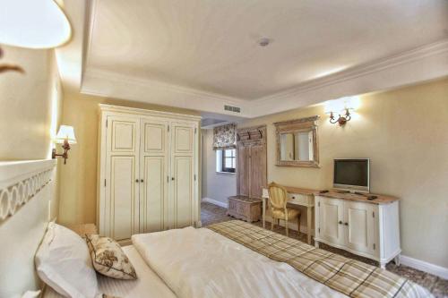 a bedroom with a bed and a desk with a television at PENSIUNEA DIMITRIOS Relaxare cu jacuzzi pe Valea Cernei in Băile Herculane