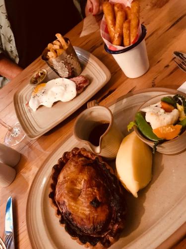 a wooden table with plates of food and french fries at The Priest House On The River in Castle Donington