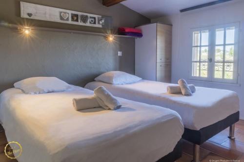 two beds in a room with white sheets and pillows at Les Garrigues de la Vallée des Baux in Paradou
