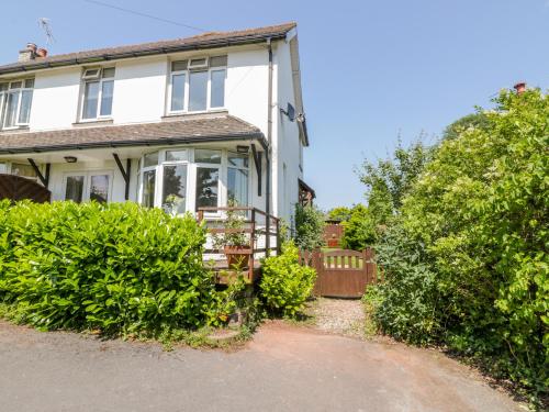 a white house with a porch and bushes at Hilltop in Totnes