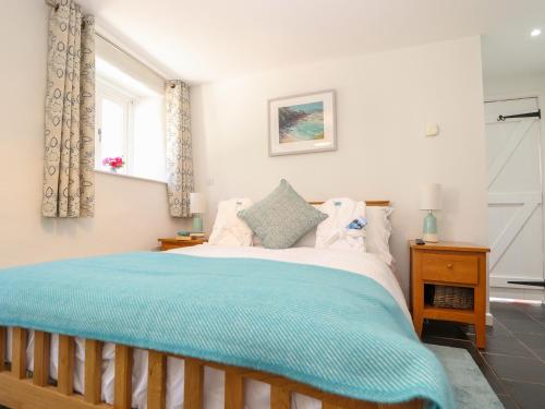 a bedroom with a large bed with a blue blanket at Sunbury Barn in St. Agnes