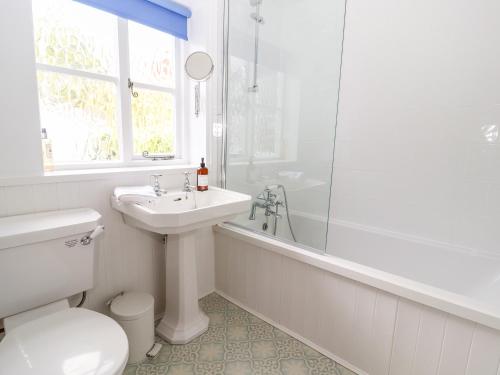 a white bathroom with a sink and a shower at Minnow Cottage in Malpas