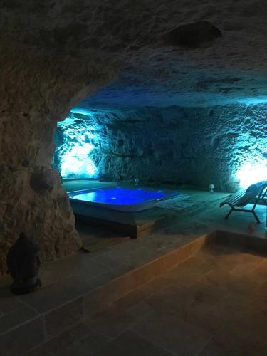 une baignoire dans une grotte aux lumières bleues dans l'établissement Le Chateau de la Barre, à Mosnes