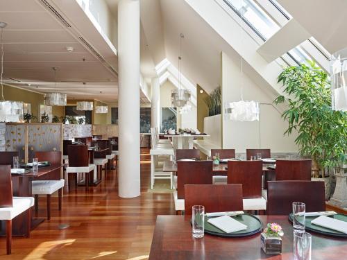 a restaurant with wooden tables and chairs and windows at Grand Hotel Wien in Vienna