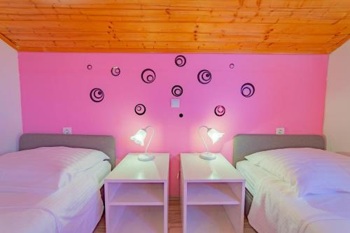 two beds in a room with a pink wall at Holiday Home Tina in Cavtat