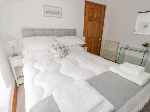 a large white bed with white sheets and pillows at Bryn Haf, New Street in Beaumaris