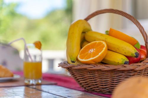 a basket of fruit on a table with a glass of orange juice at Holiday Home Tina in Cavtat