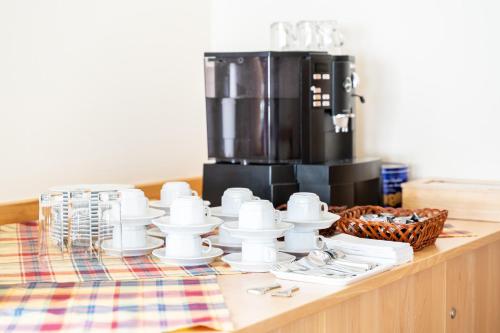 a table with cups and plates and a coffee maker at Hotel Rieder in Wiesemscheid