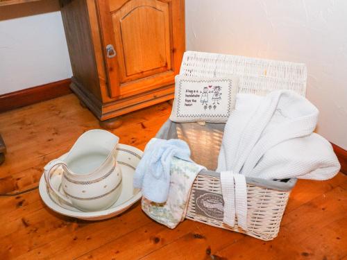 einen Korb mit Geschirr und Handtüchern auf einem Holzboden in der Unterkunft Woodleigh Cottage in Ballycastle