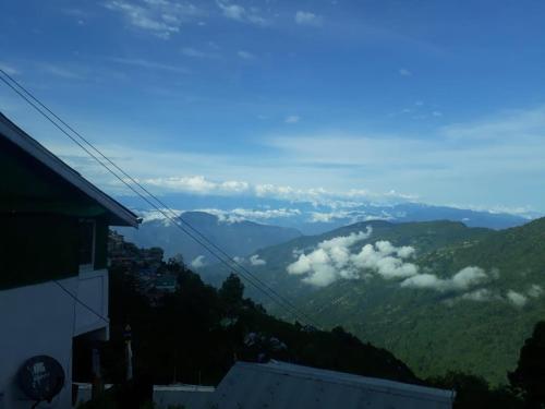 a view of a mountain with clouds in the valley at Vamoose Quaint Wood Cottage in Darjeeling