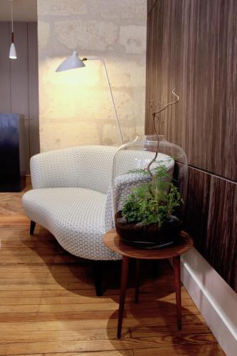 a living room with a chair and a plant on a table at Hôtel de Tourny - Boutique Hôtel Bordeaux Centre in Bordeaux