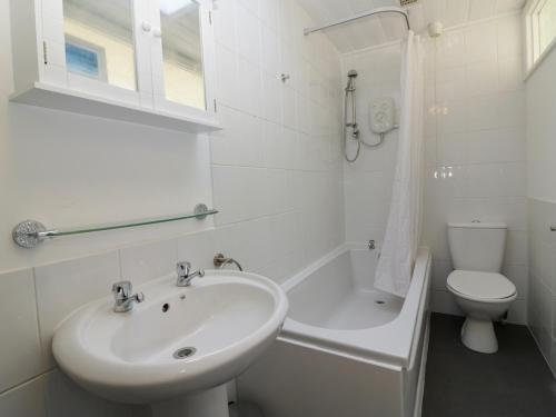 a white bathroom with a sink and a toilet at Harbourside Cottage in Torquay