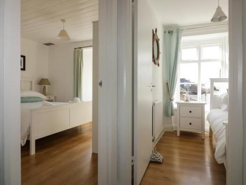 a white bedroom with a bed and a window at Harbourside Cottage in Torquay
