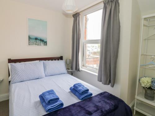 zwei Handtücher auf einem Bett in einem Schlafzimmer mit Fenster in der Unterkunft Midsummer Cottage in Stratford-upon-Avon