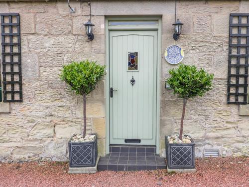 a front door of a stone house with two potted plants at Iona Cottage in Duns