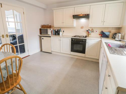 a kitchen with white cabinets and a table and chairs at 1 The Moorings in Newry